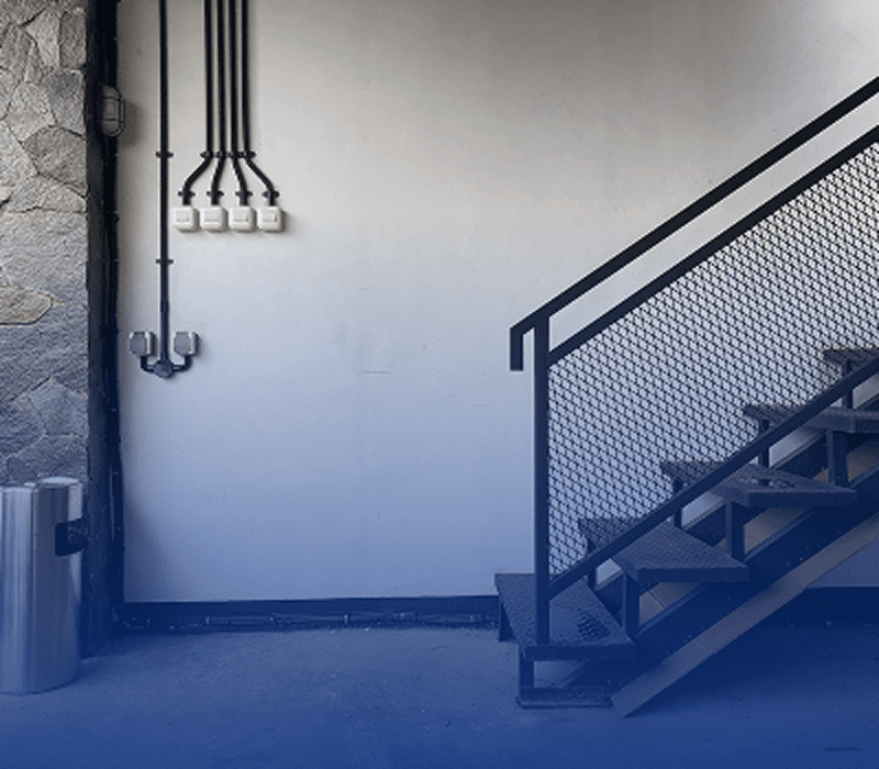 Industrial staircase with metal railing and pipes.